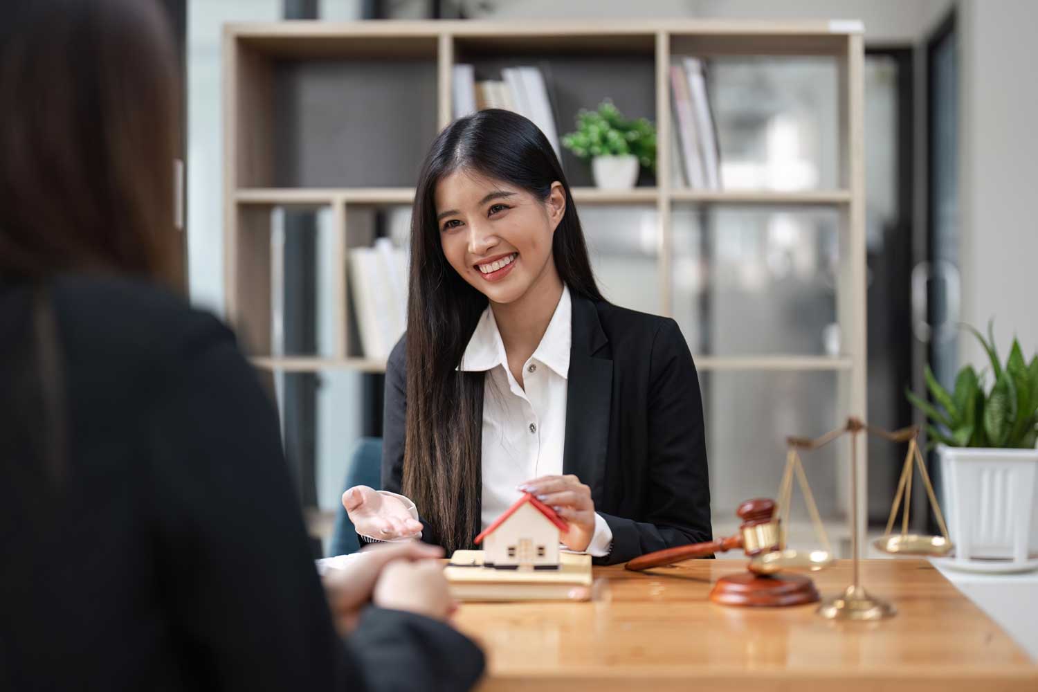 Friendly SKB Law Firm lawyer discussing with a client, legal scales and gavel on the table, office environment.