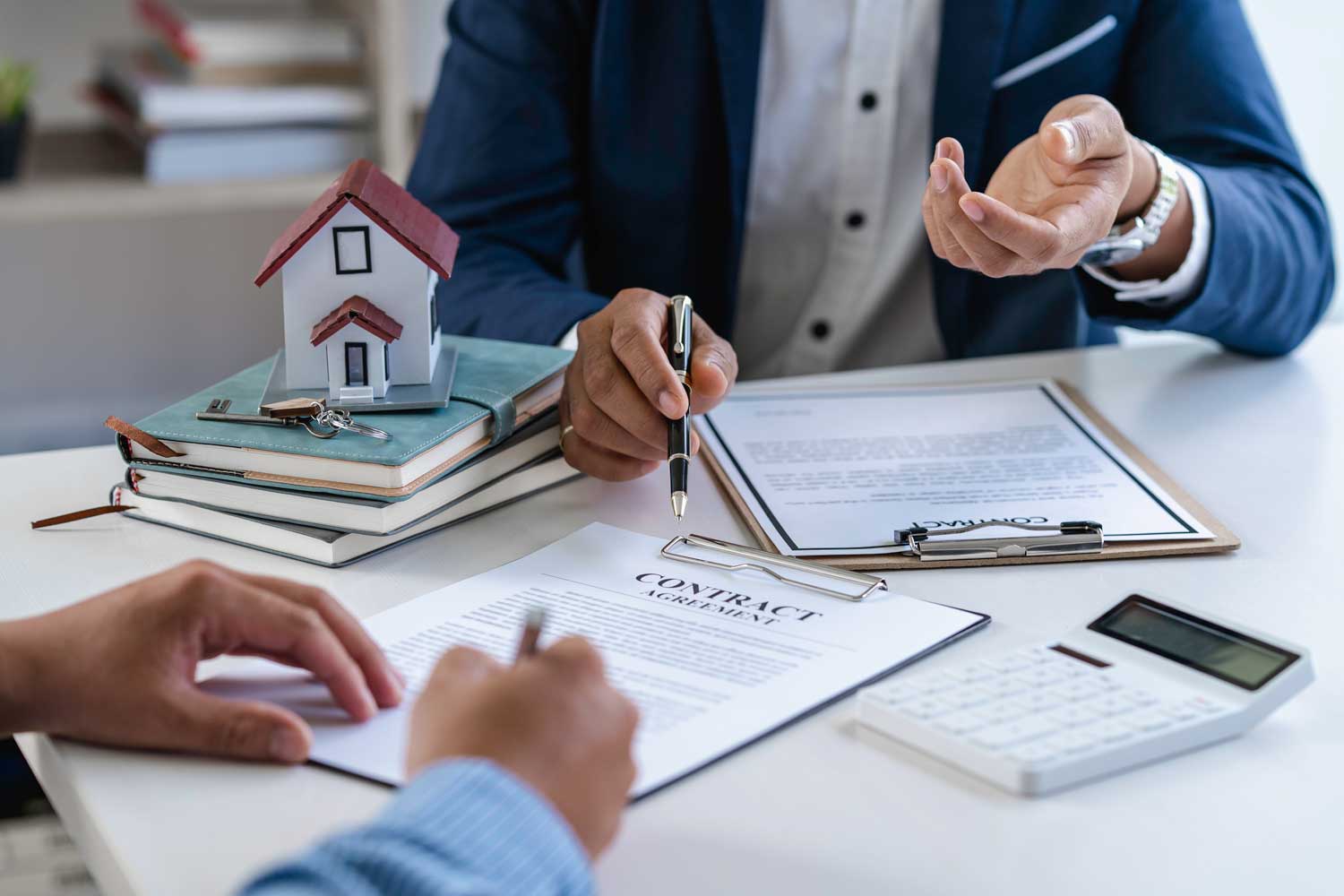 Client signing a contract at SKB Law Firm with an attorney, house model and keys on the table, symbolizing a real estate transaction.