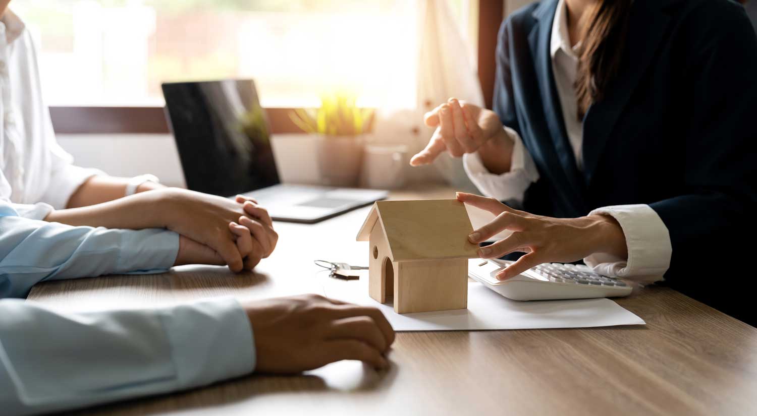 Consultation at SKB Law Firm with a lawyer explaining housing details to clients, wooden house model on the table.