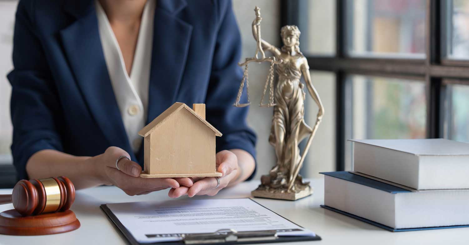 A girl in Law Firm holding a house model, symbolizing property law, with legal books and a statue of justice in background.